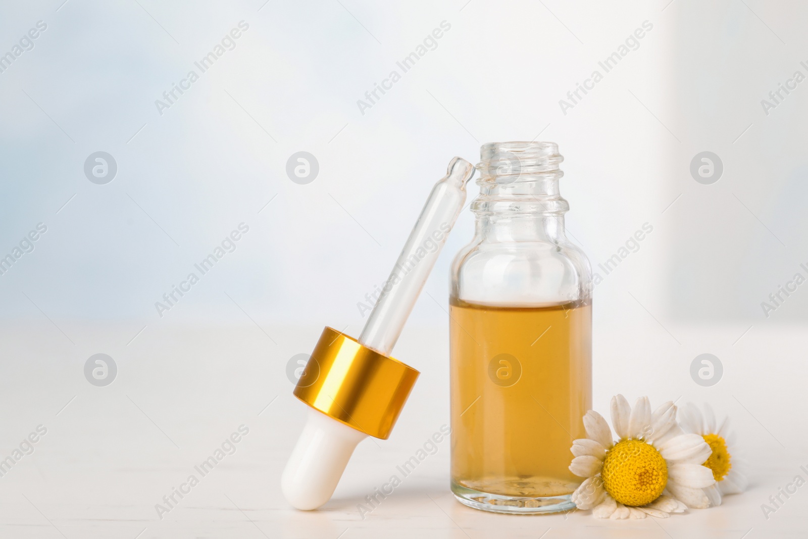 Photo of Composition with bottle of chamomile essential oil on table. Space for text