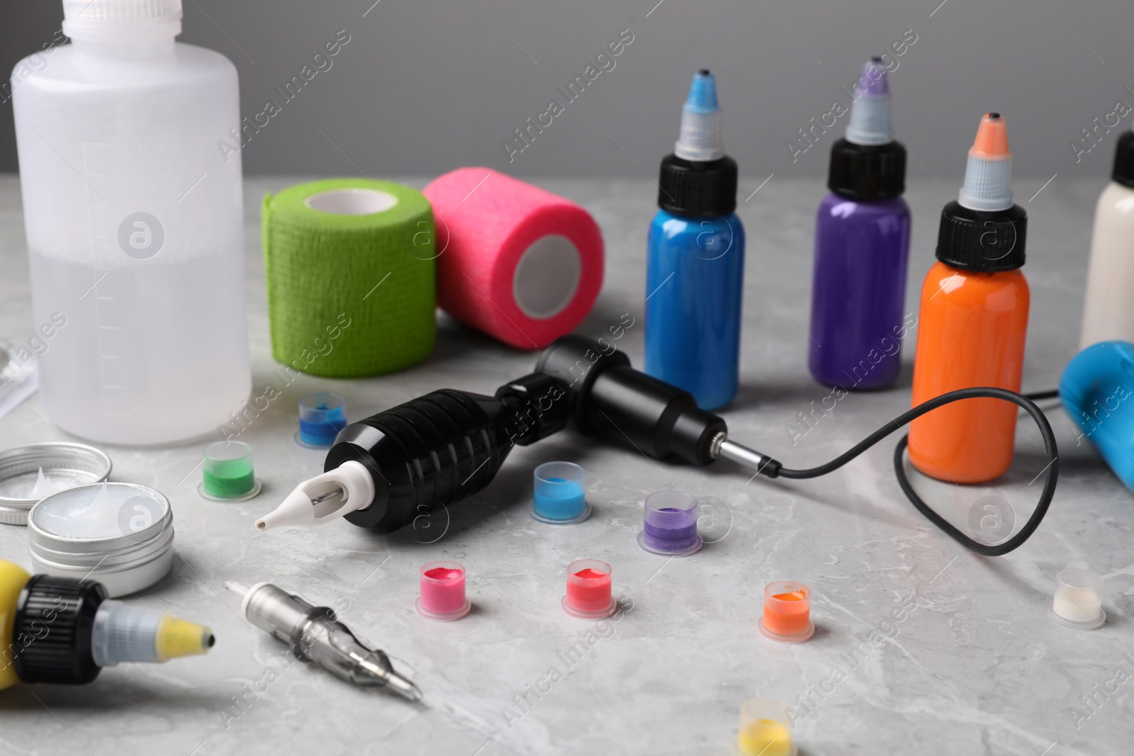 Photo of Tattoo machine and professional tools on light grey table