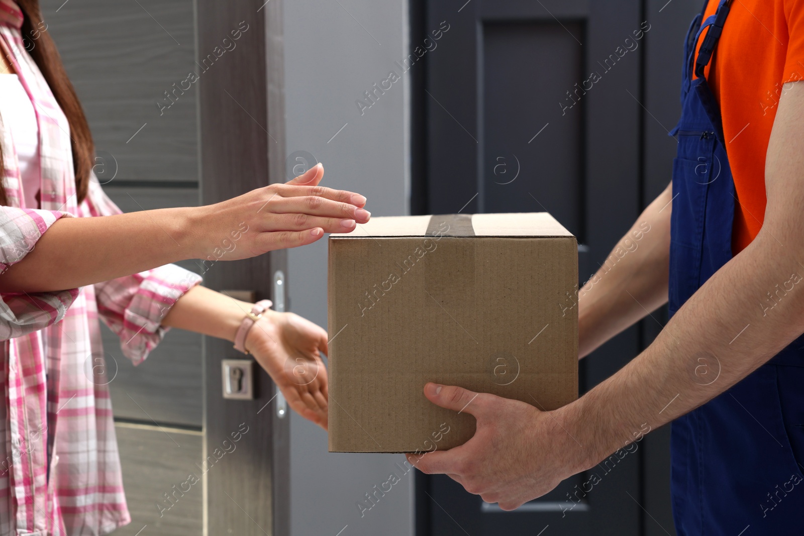 Photo of Woman receiving parcel from courier at home, closeup