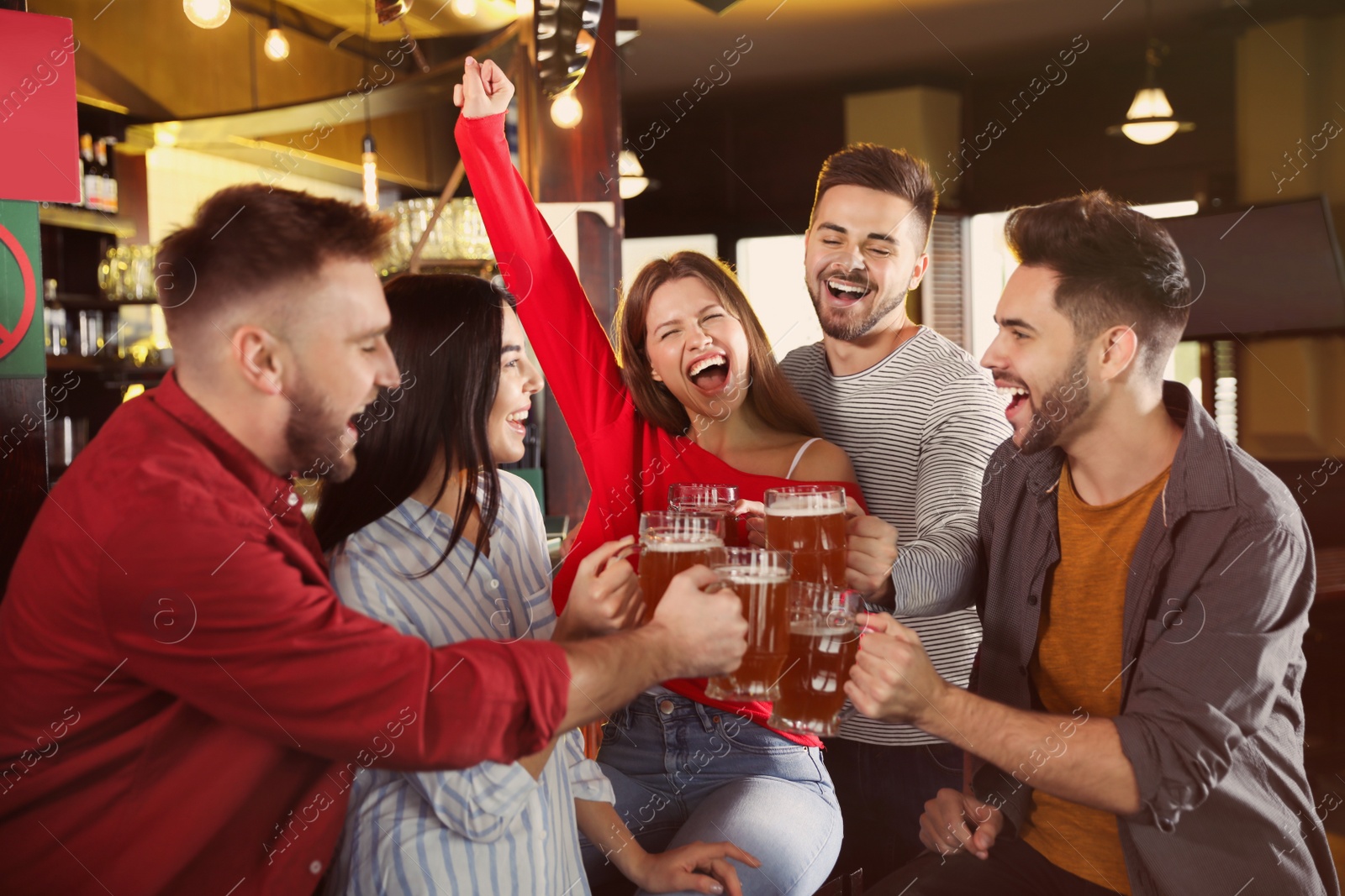 Photo of Group of friends celebrating victory of favorite football team in sport bar