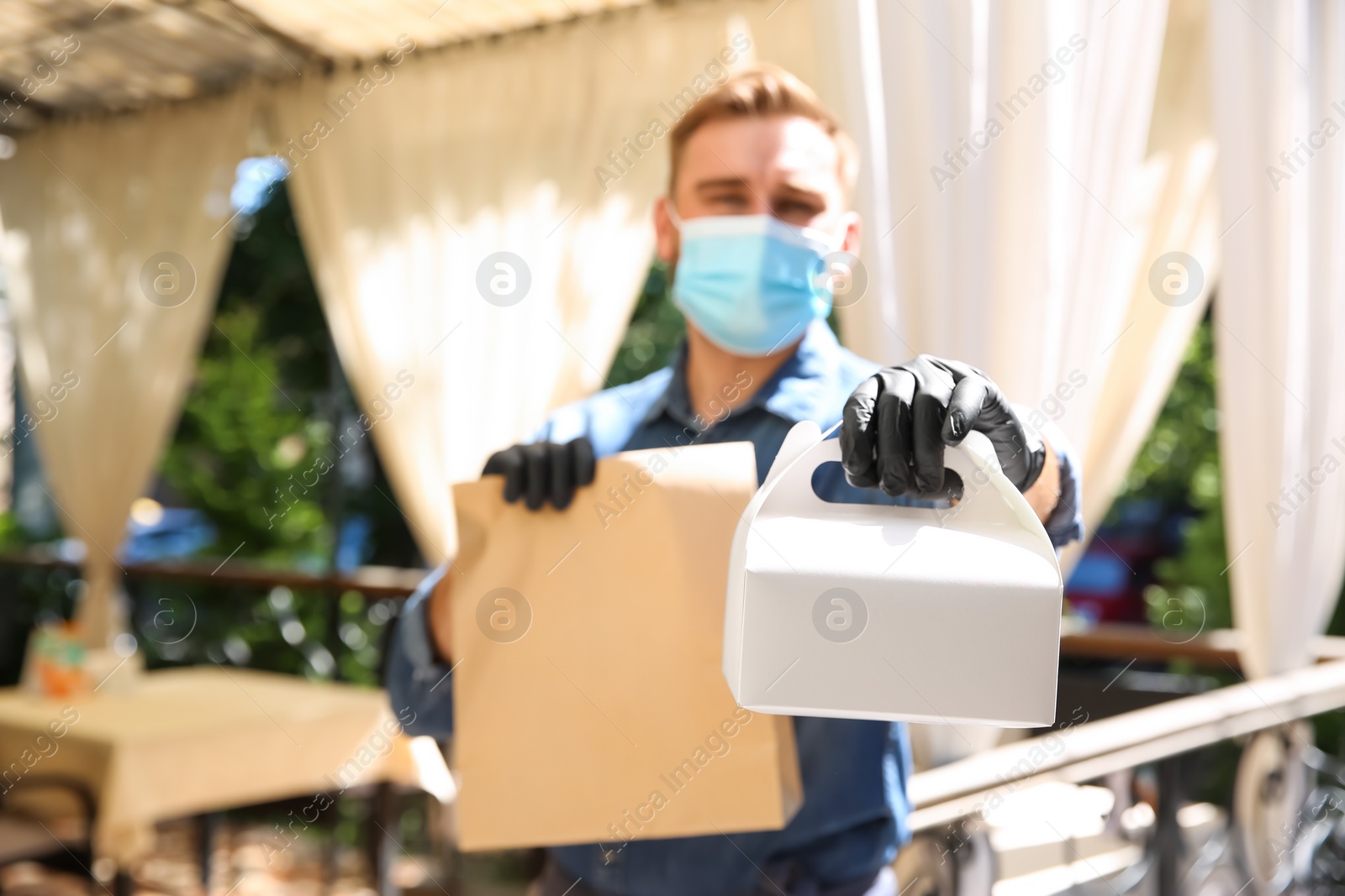 Photo of Waiter with packed takeout order in restaurant, focus on hand. Food service during coronavirus quarantine