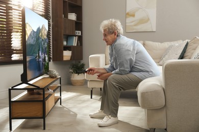 Photo of Elderly woman with poor posture watching TV in living room