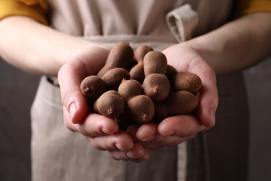 Photo of Woman holding fresh ripe tamarinds, closeup view