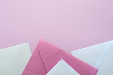 Colorful paper envelopes on pink background, flat lay. Space for text