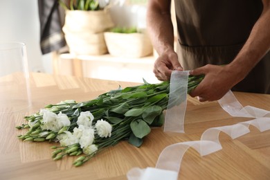 Photo of Florist making beautiful bouquet at table in workshop, closeup