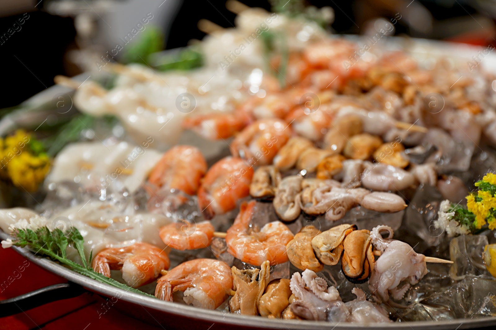 Photo of Seafood skewers served in dish with ice, closeup