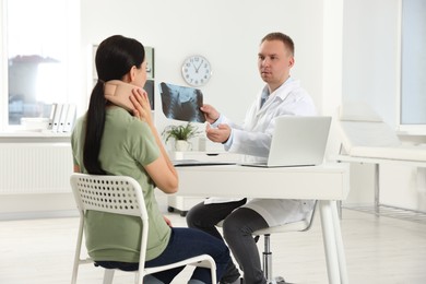 Photo of Doctor with neck MRI image consulting patient in clinic