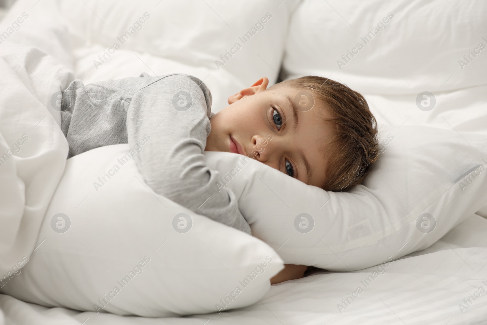 Photo of Sad little boy in bed at home
