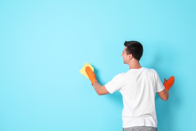 Man in gloves cleaning color wall with rag