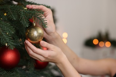 Photo of Woman decorating Christmas tree at home, closeup