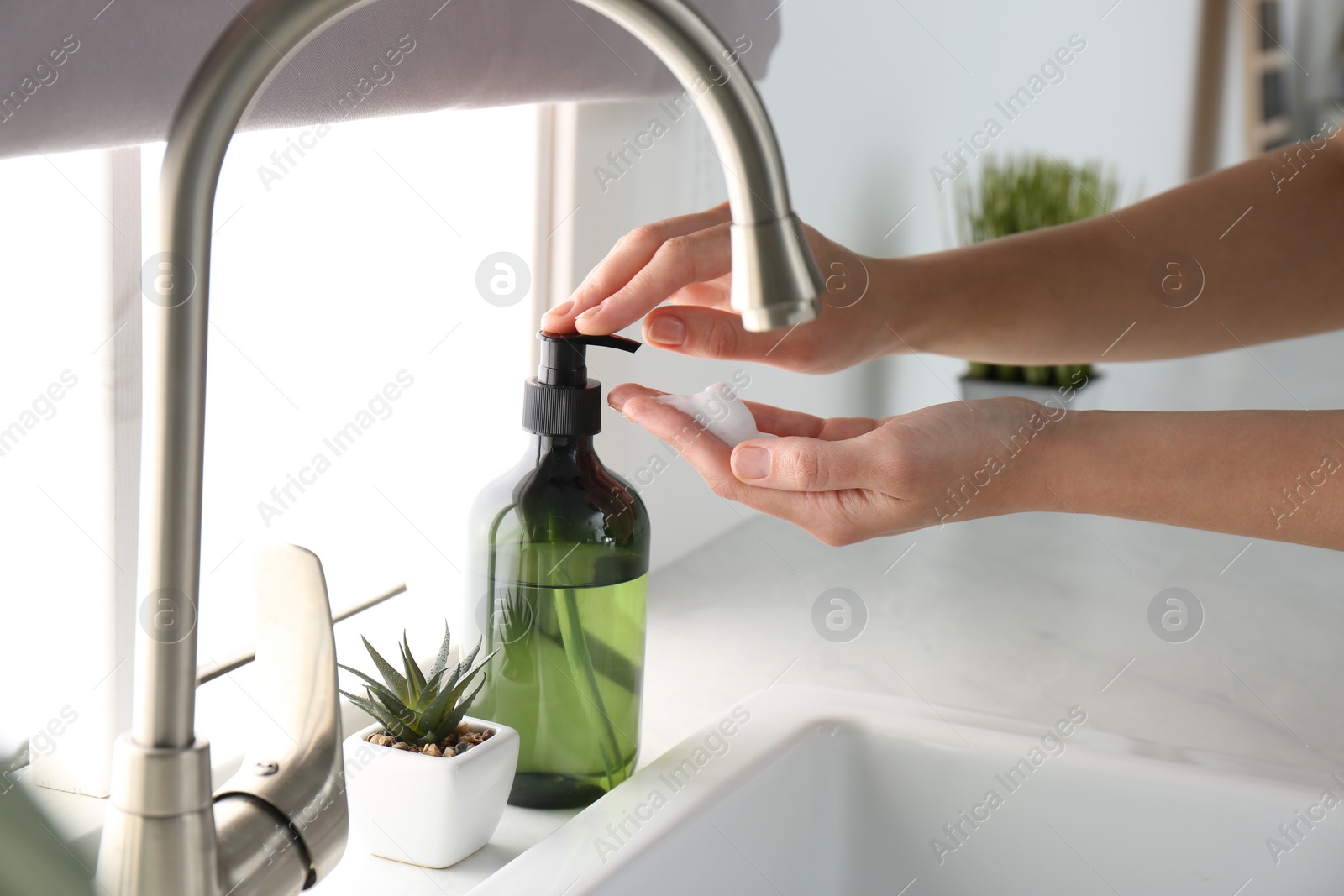 Photo of Woman using soap dispenser in kitchen, closeup