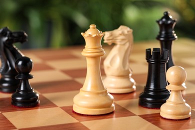 Photo of Different chess pieces on game board against blurred background, closeup