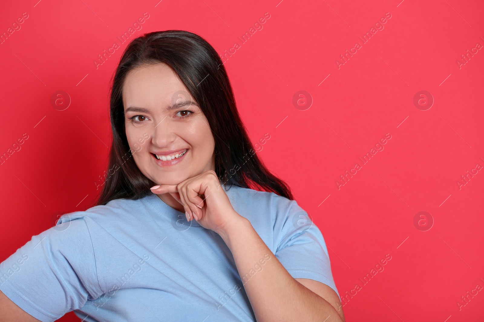 Photo of Beautiful overweight woman with charming smile on red background. Space for text