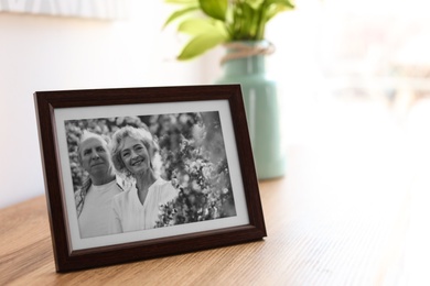 Photo of Portrait of senior couple in frame on table indoors. Space for text