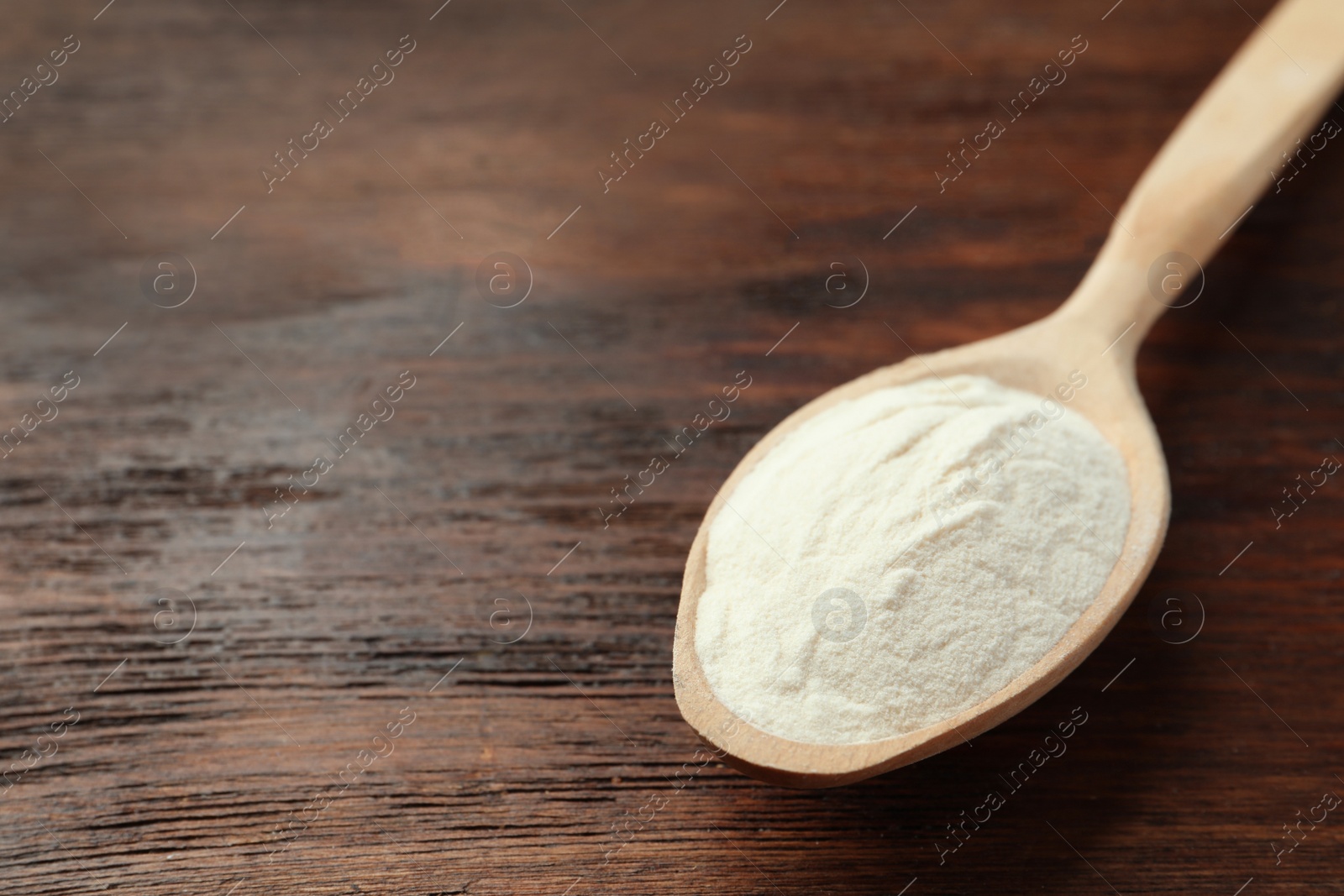 Photo of Spoon of agar-agar powder on wooden table, closeup. Space for text