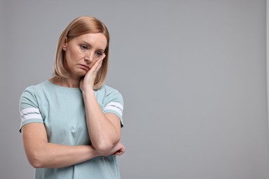 Photo of Portrait of sad woman on grey background. Space for text