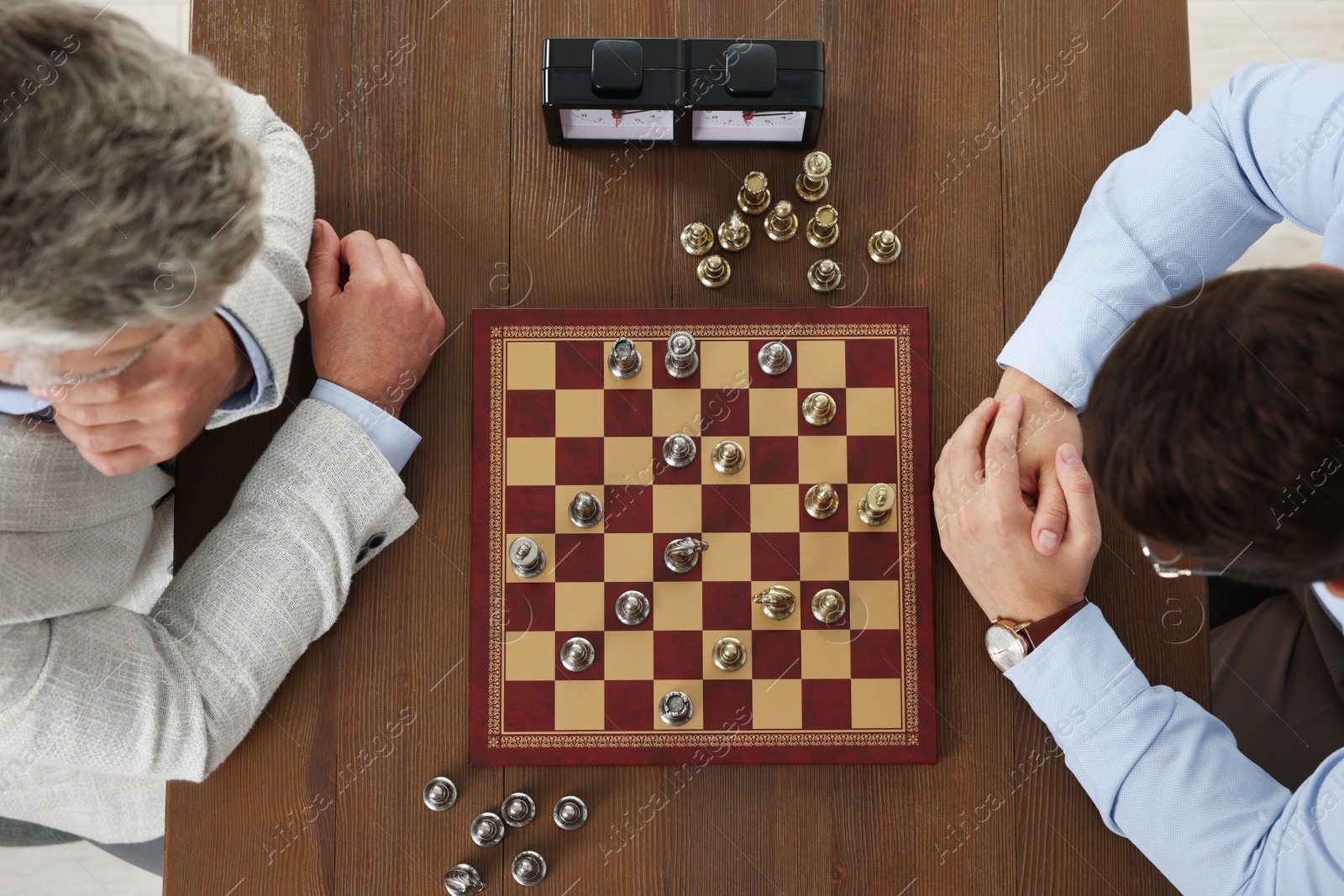 Photo of Men playing chess during tournament at wooden table, top view