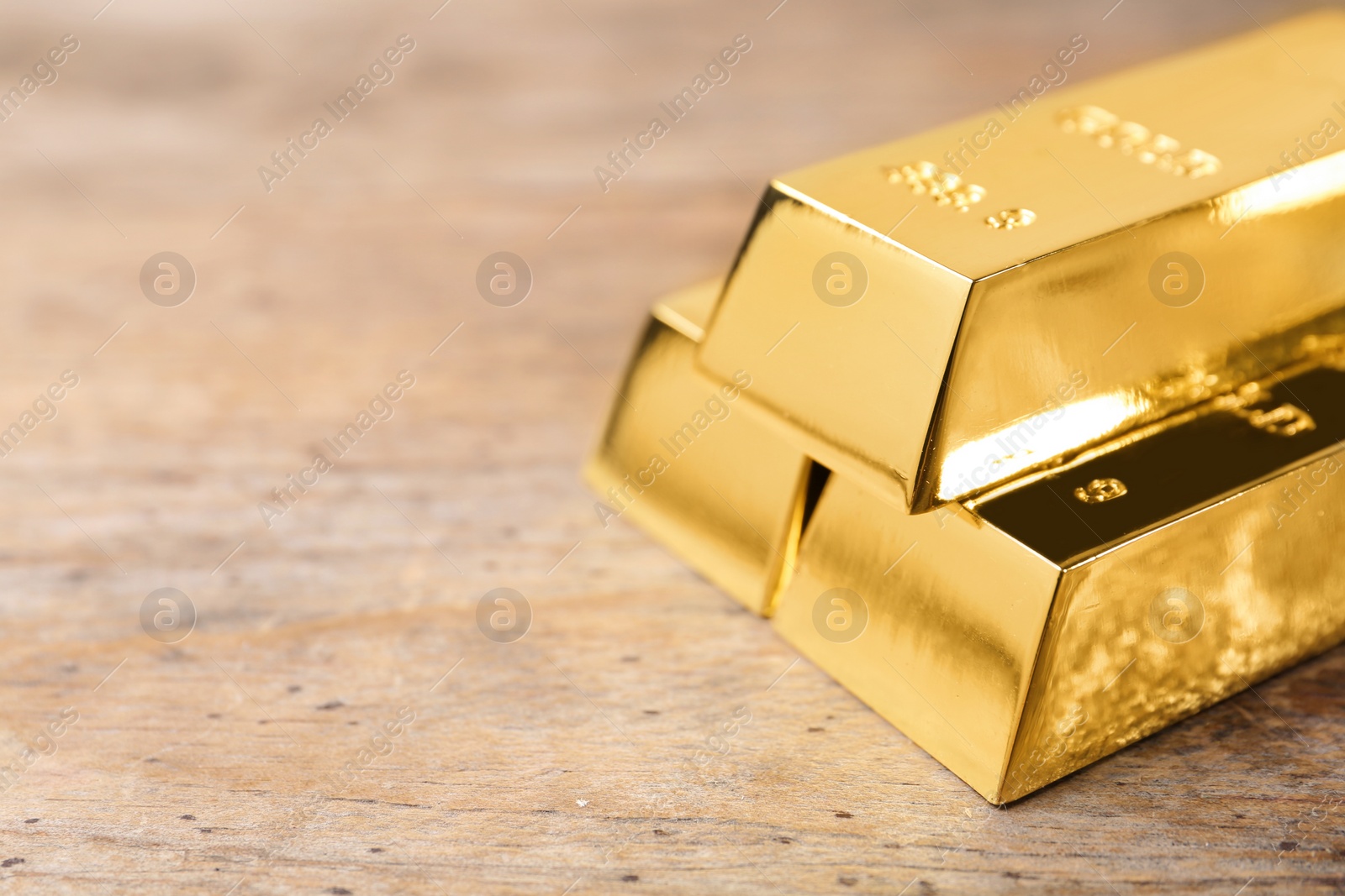 Photo of Shiny gold bars on wooden background. Space for text