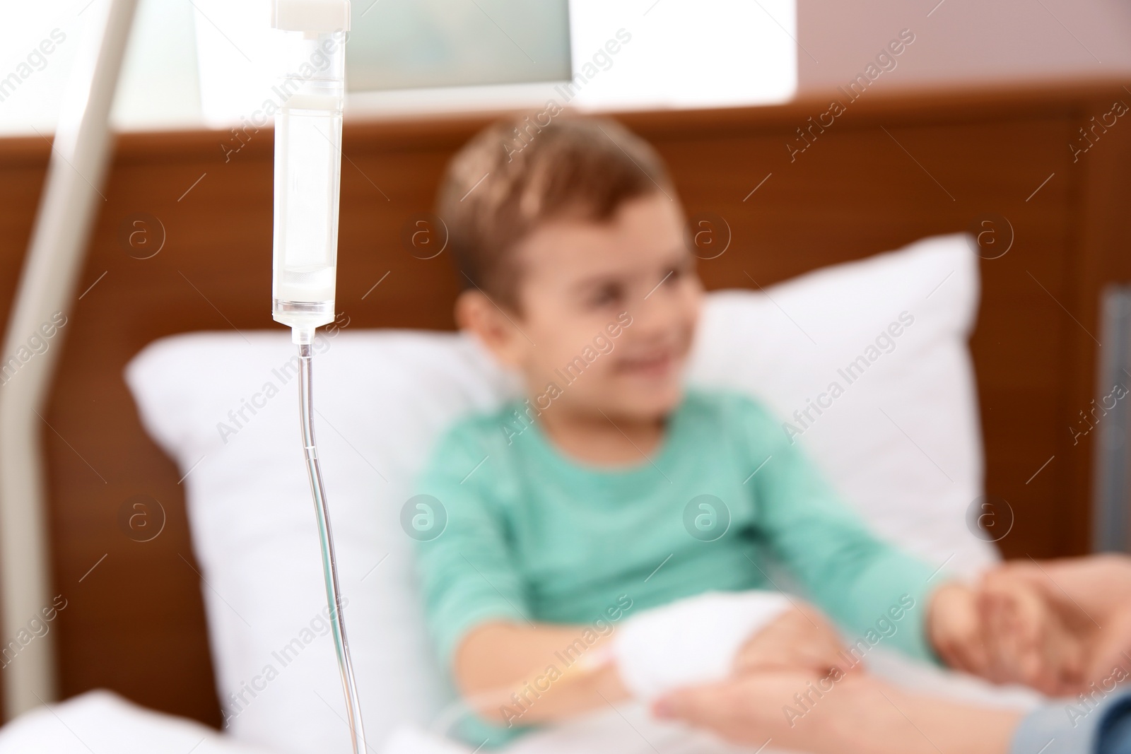 Photo of Woman visiting her little child with intravenous infusion in hospital, focus on drip chamber