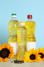 Bottles of cooking oil, sunflowers and seeds on white table