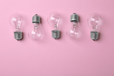 Photo of New incandescent lamp bulbs on pink background, top view. Space for text