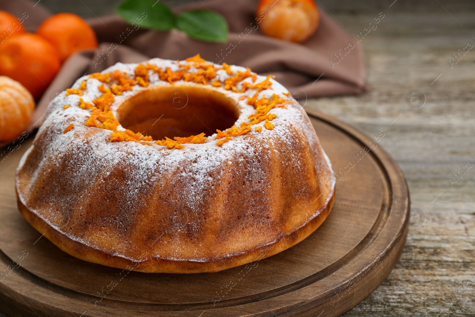 Photo of Homemade yogurt cake with tangerines and powdered sugar on wooden table, closeup