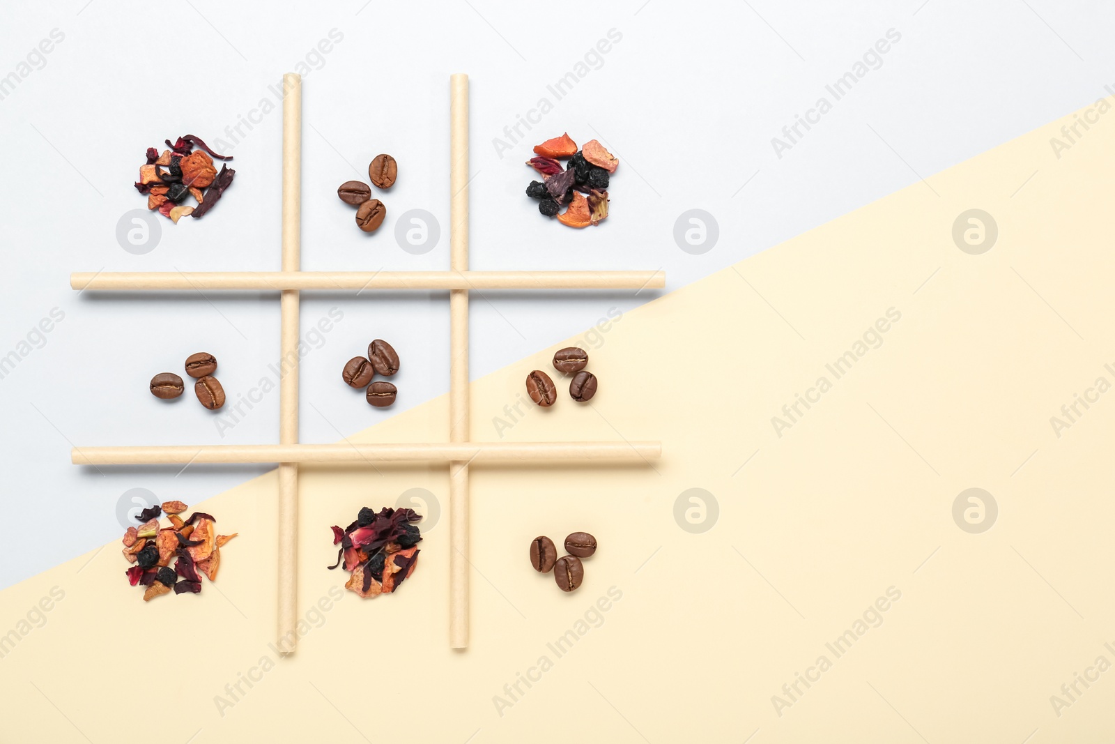 Photo of Tic tac toe game made with coffee beans and dry tea leaves on color background, top view