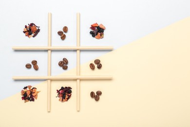 Photo of Tic tac toe game made with coffee beans and dry tea leaves on color background, top view