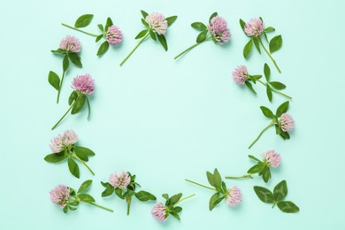 Photo of Frame of beautiful clover flowers on turquoise background, flat lay. Space for text