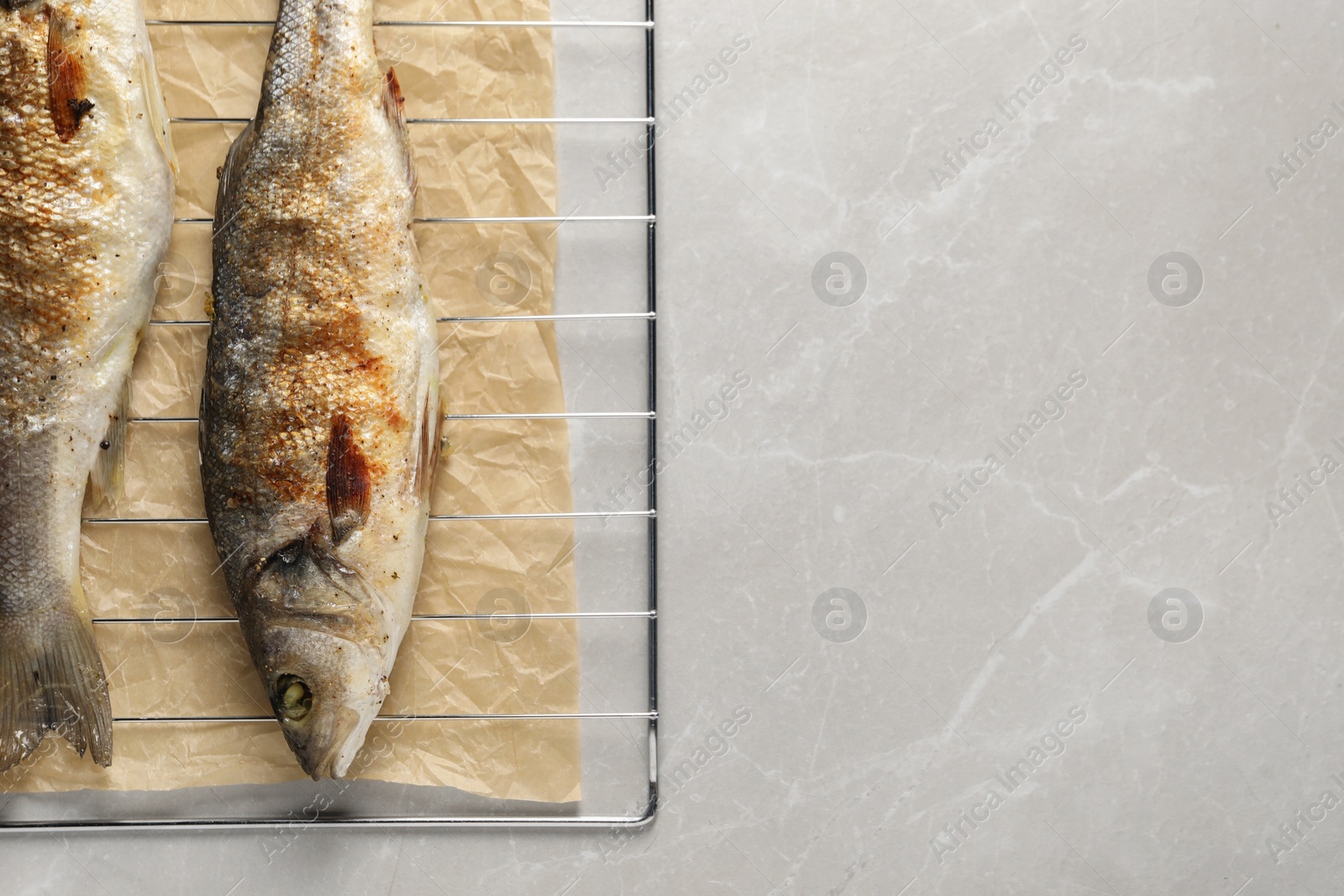 Photo of Baked fish on light marble table, top view. Space for text