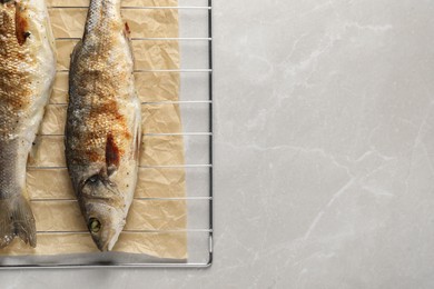 Photo of Baked fish on light marble table, top view. Space for text