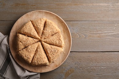 Photo of Delicious cut Napoleon cake on wooden table, top view. Space for text