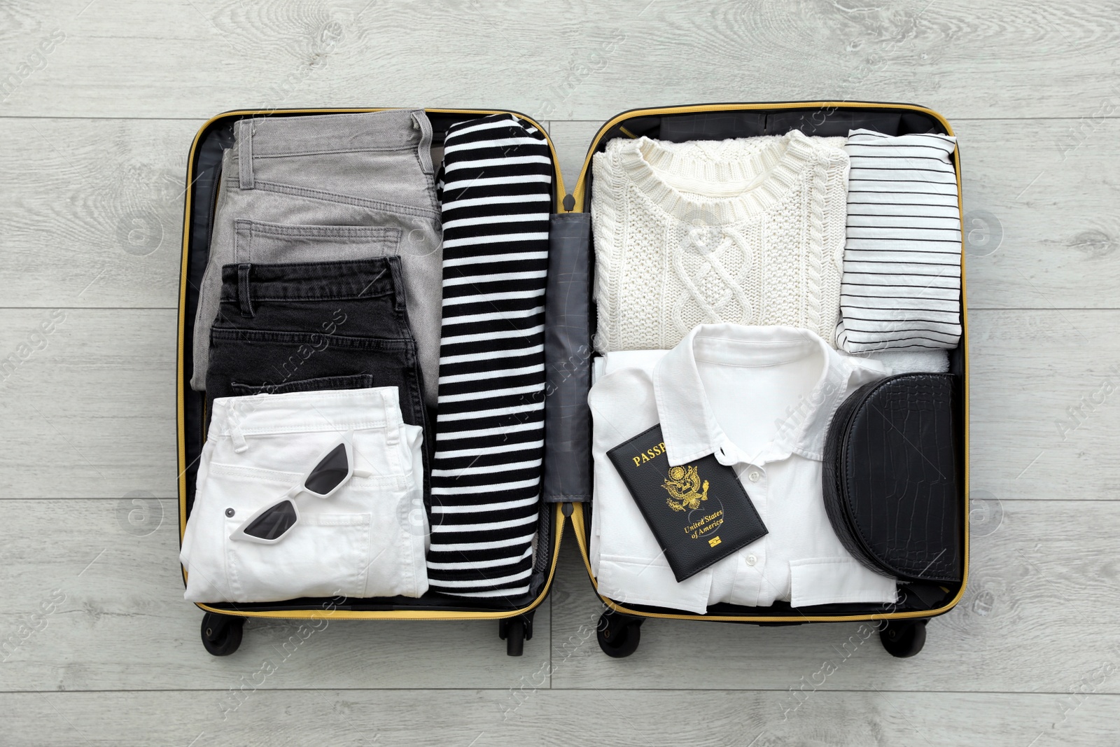 Photo of Open suitcase with clothes, passport and accessories on floor, top view