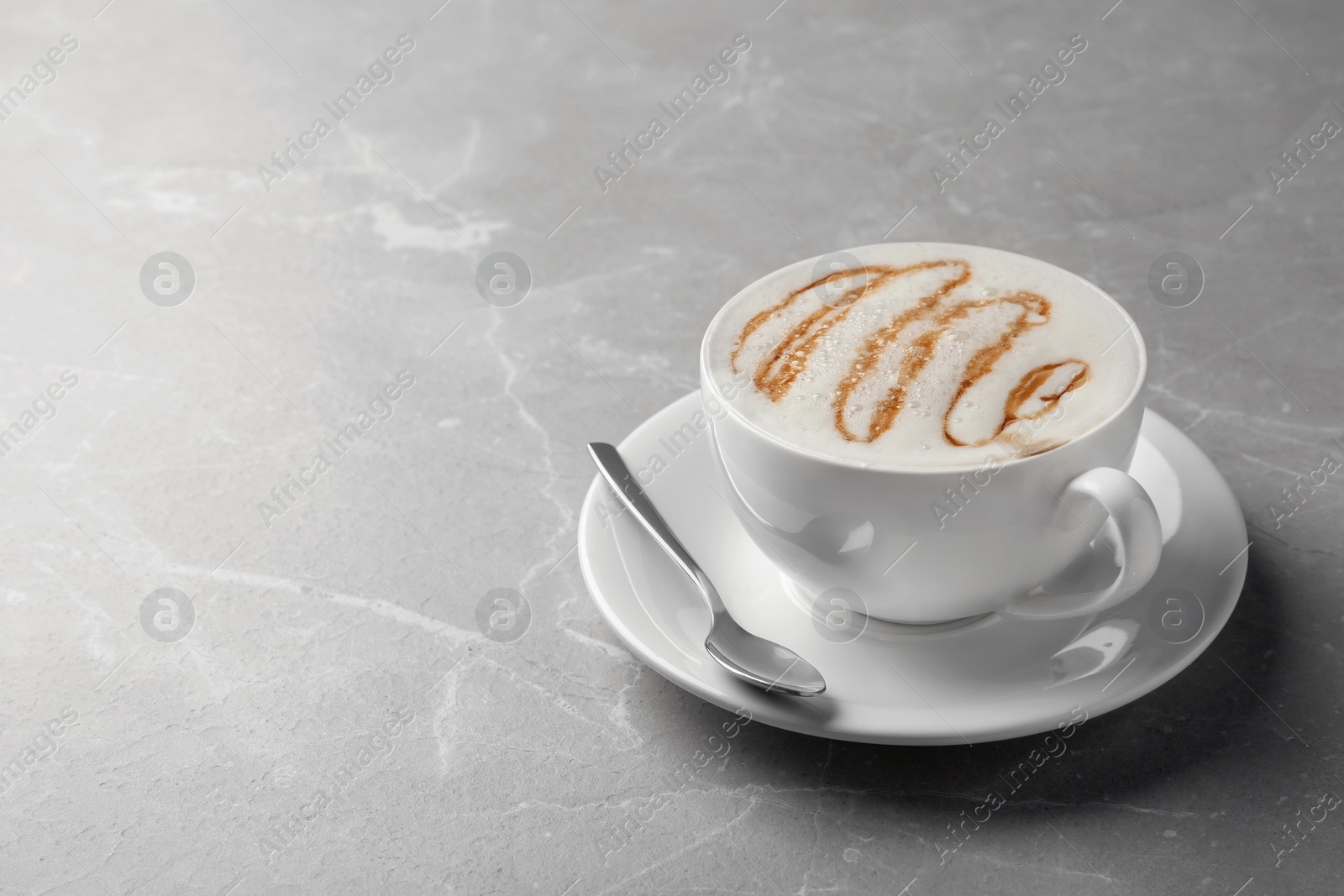 Photo of Cup of tasty caramel macchiato on table. Space for text