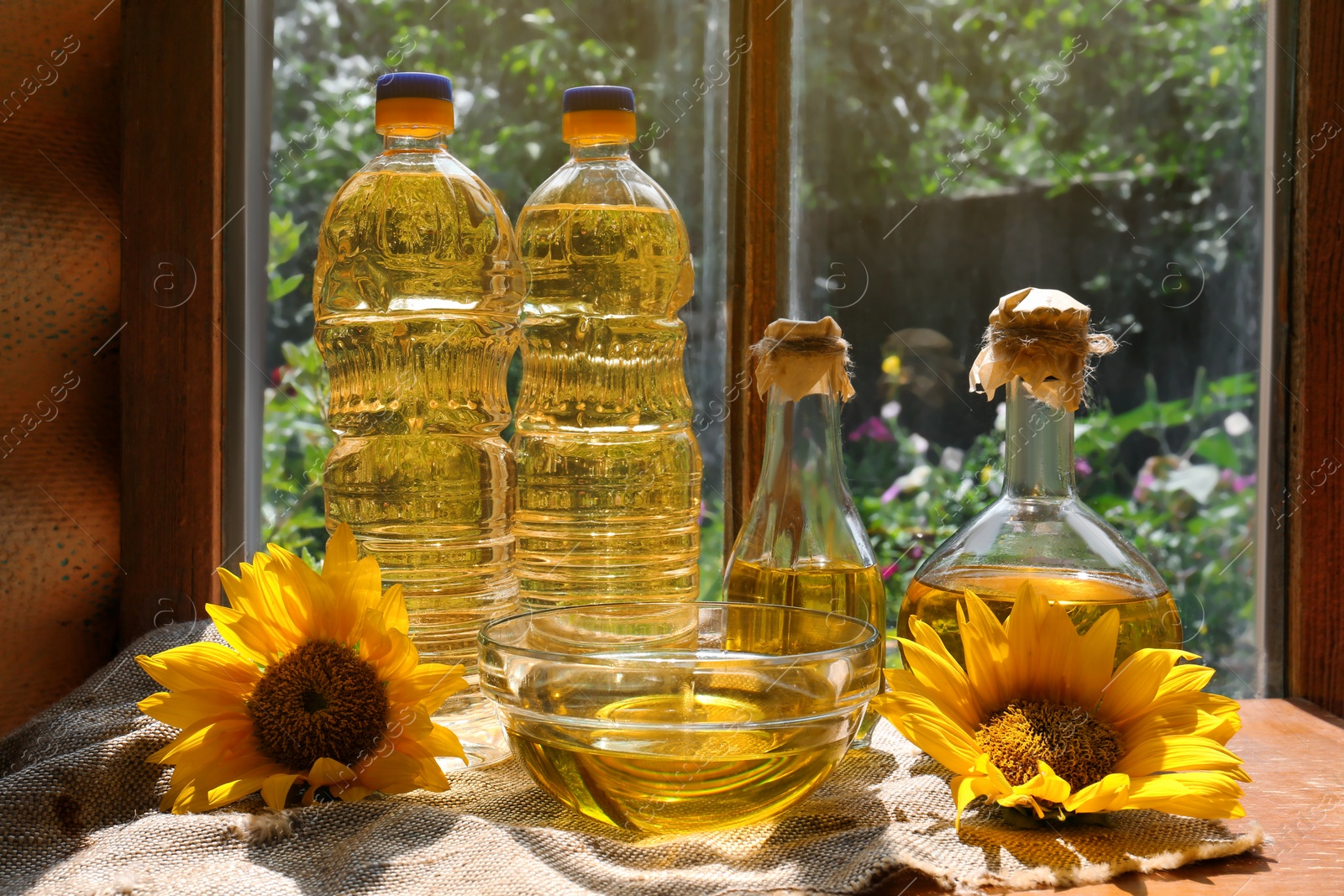 Photo of Organic sunflower oil and flowers on window sill indoors