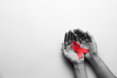 Image of World AIDS disease day. Woman holding red awareness ribbon on white background, top view with space for text