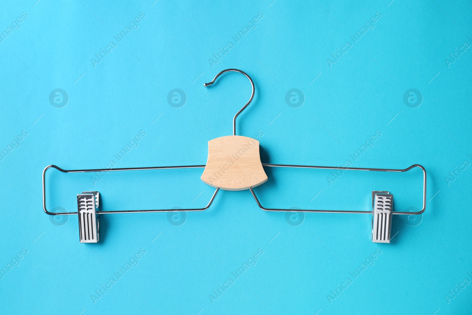 Photo of Wooden hanger with clips on light blue background, top view