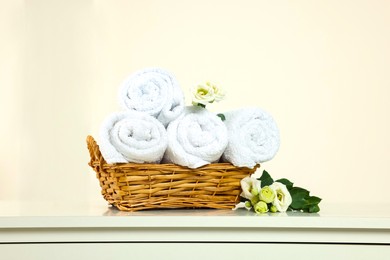 Photo of Soft folded towels and flowers on white table