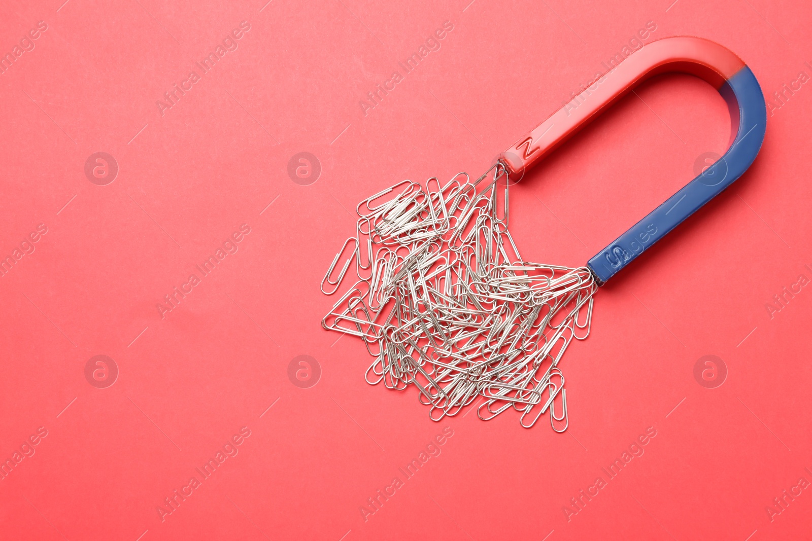 Photo of Magnet attracting paper clips on color background, top view with space for text