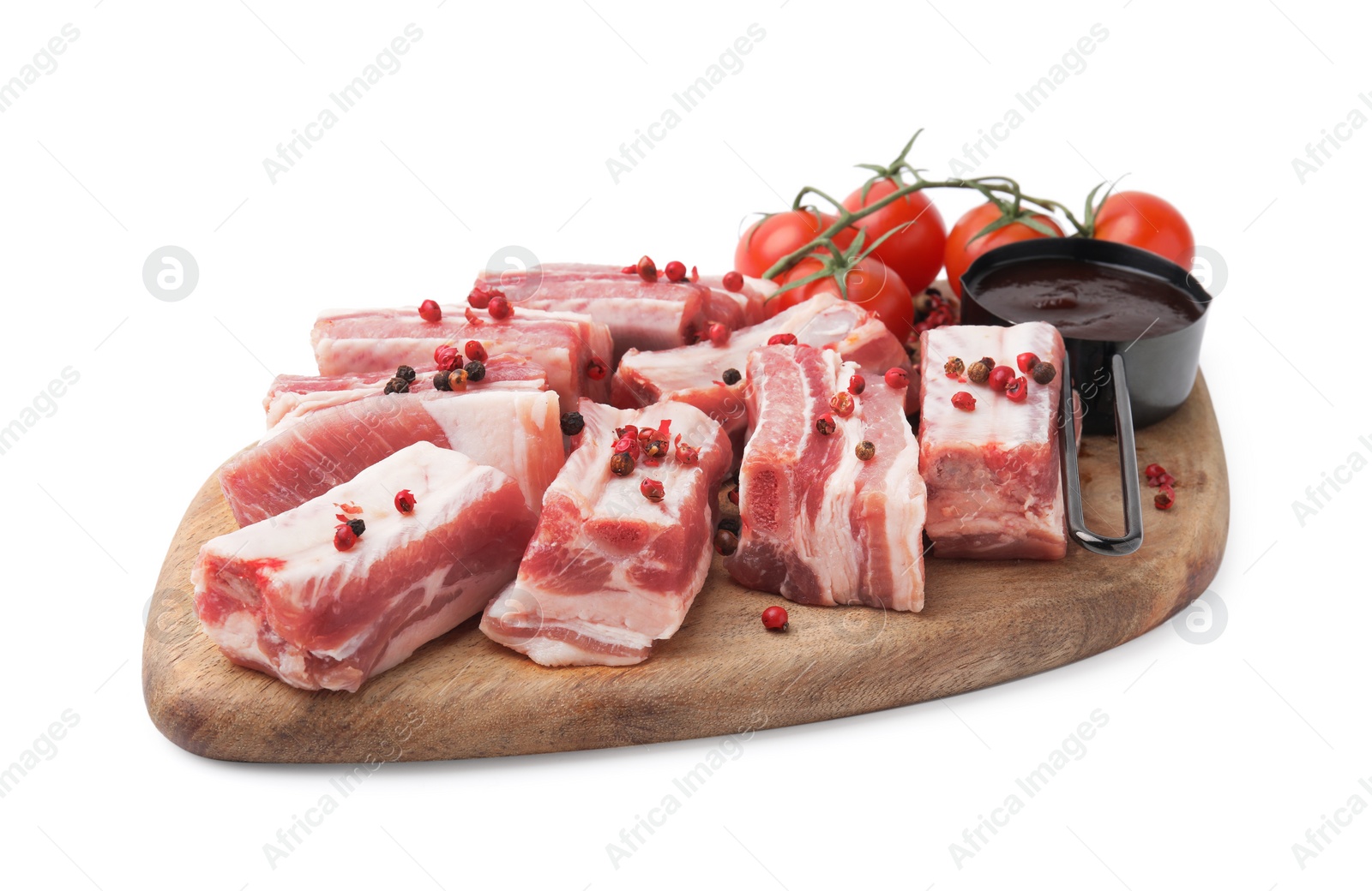 Photo of Cut raw pork ribs with peppercorns, tomatoes and sauce isolated on white