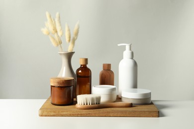 Photo of Different bath accessories and spikes on white table against grey background