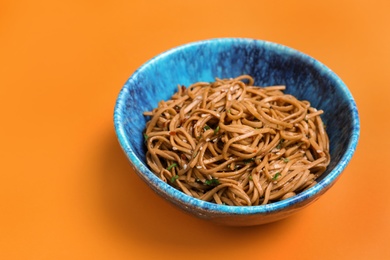 Photo of Bowl of buckwheat noodles on color background