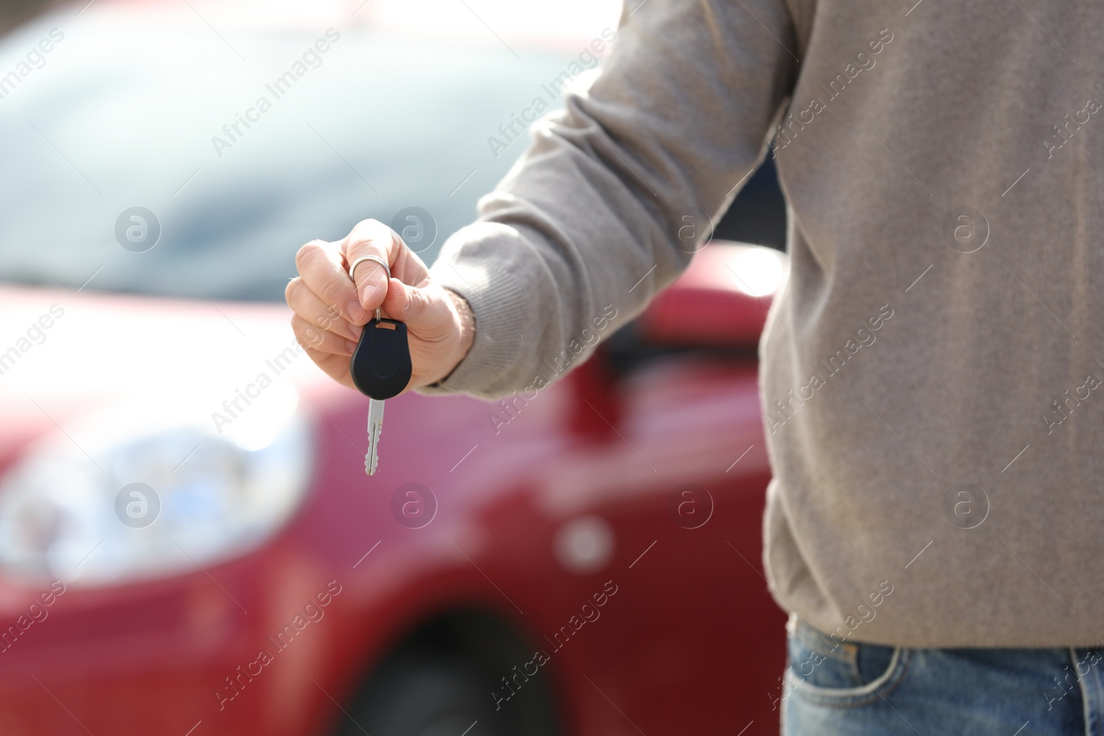 Photo of Man holding key in modern auto dealership, closeup. Buying new car