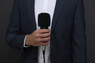 Photo of Professional journalist with microphone on dark background, closeup
