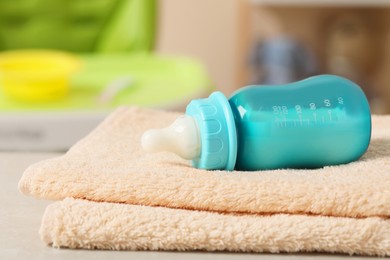 Photo of Feeding bottle with baby formula and towels on table indoors
