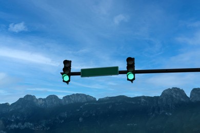 View of traffic lights, road sign and mountains