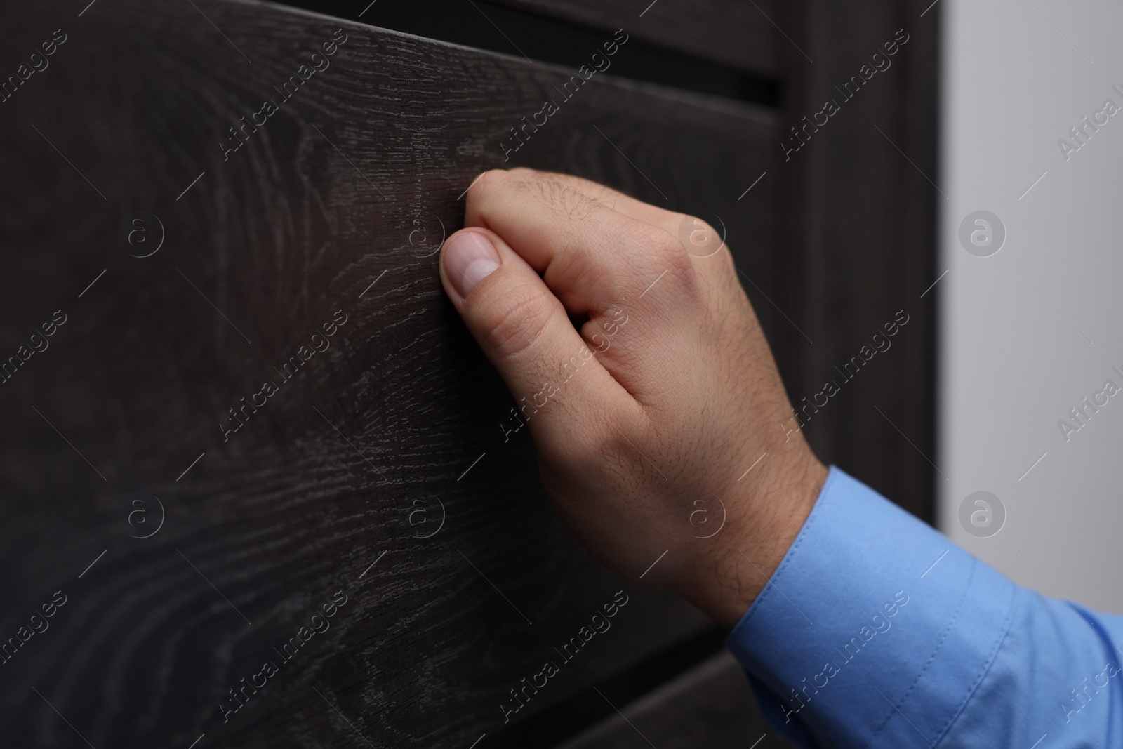 Photo of Collection agent knocking on wooden door, closeup