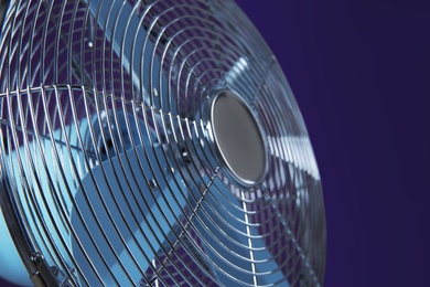 Photo of Modern electric fan on violet background, closeup