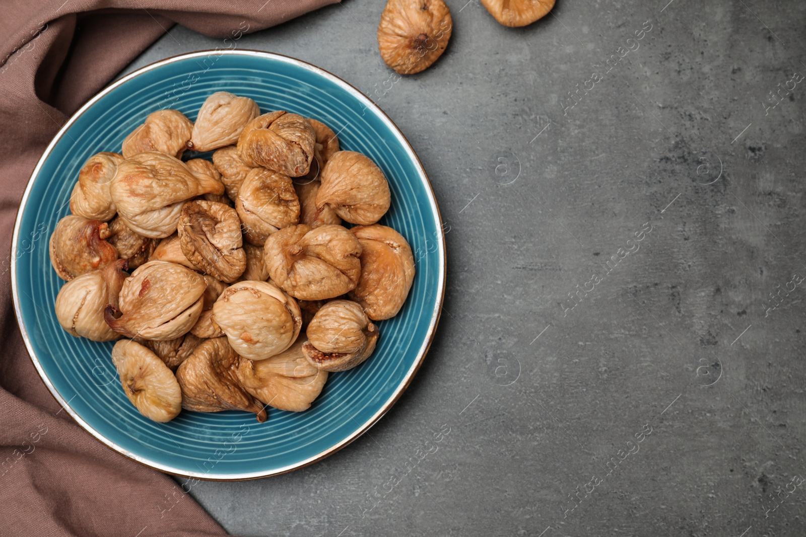 Photo of Plate of dried figs on grey background, top view with space for text. Healthy fruit