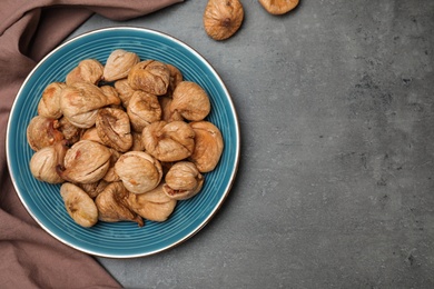 Photo of Plate of dried figs on grey background, top view with space for text. Healthy fruit